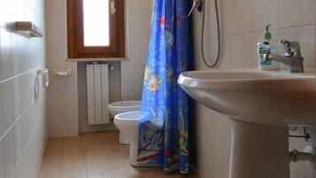 Une salle de bain comprenant des toilettes, un lavabo, une douche et une fenêtre.