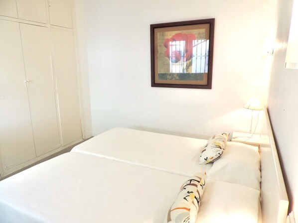 A hotel room with a bed, a wardrobe, a framed picture on the wall, and a bedside lamp.