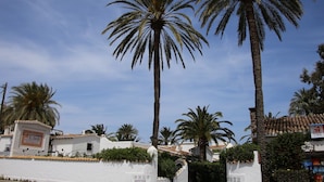 A white building with a sign that reads "Villasperre El Oasis" and a palm tree in front. - Villa LA TARDE 1ª Línea Playa (Denia)