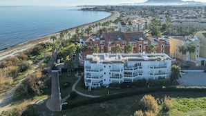 A coastal hotel with multiple floors, a beach view, and a mountainous backdrop. - LES PORTELLES Nº57 1ª Línea Playa (Denia)