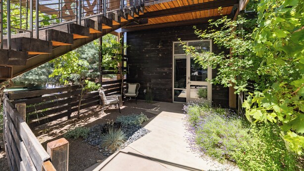 A modern outdoor patio with a wooden staircase, seating area, and a variety of plants. - Sleek Baca Railyard Gem by Cafecito w/ Patio, Laundry, Full Kitchen (Santa Fe)