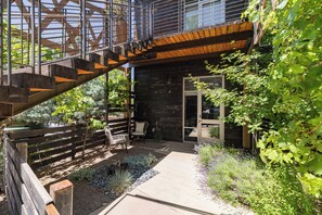 A modern outdoor patio with a wooden staircase, seating area, and a variety of plants. - Sleek Baca Railyard Gem by Cafecito w/ Patio, Laundry, Full Kitchen (Santa Fe)