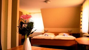 A hotel room with a bed, a bedside table, and a vase with flowers on a red table runner. - Havergoh Wander- & Fahrrad-Hotel (Horn-Bad Meinberg)