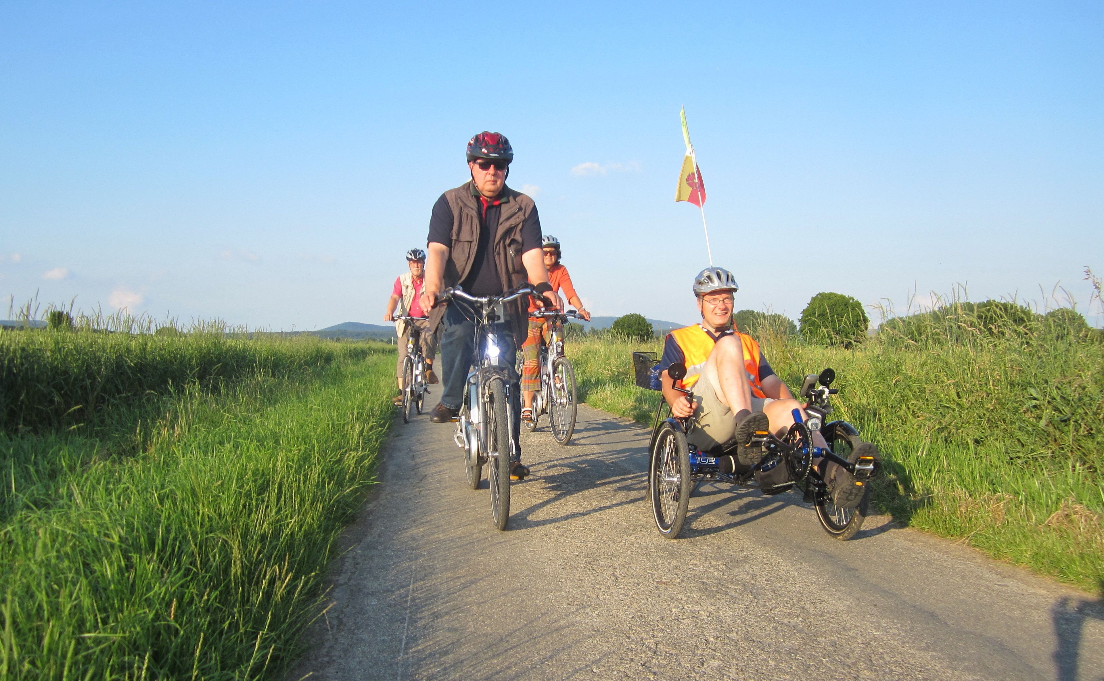 Un grupo de personas en bicicleta y una motocicleta en una carretera rural.