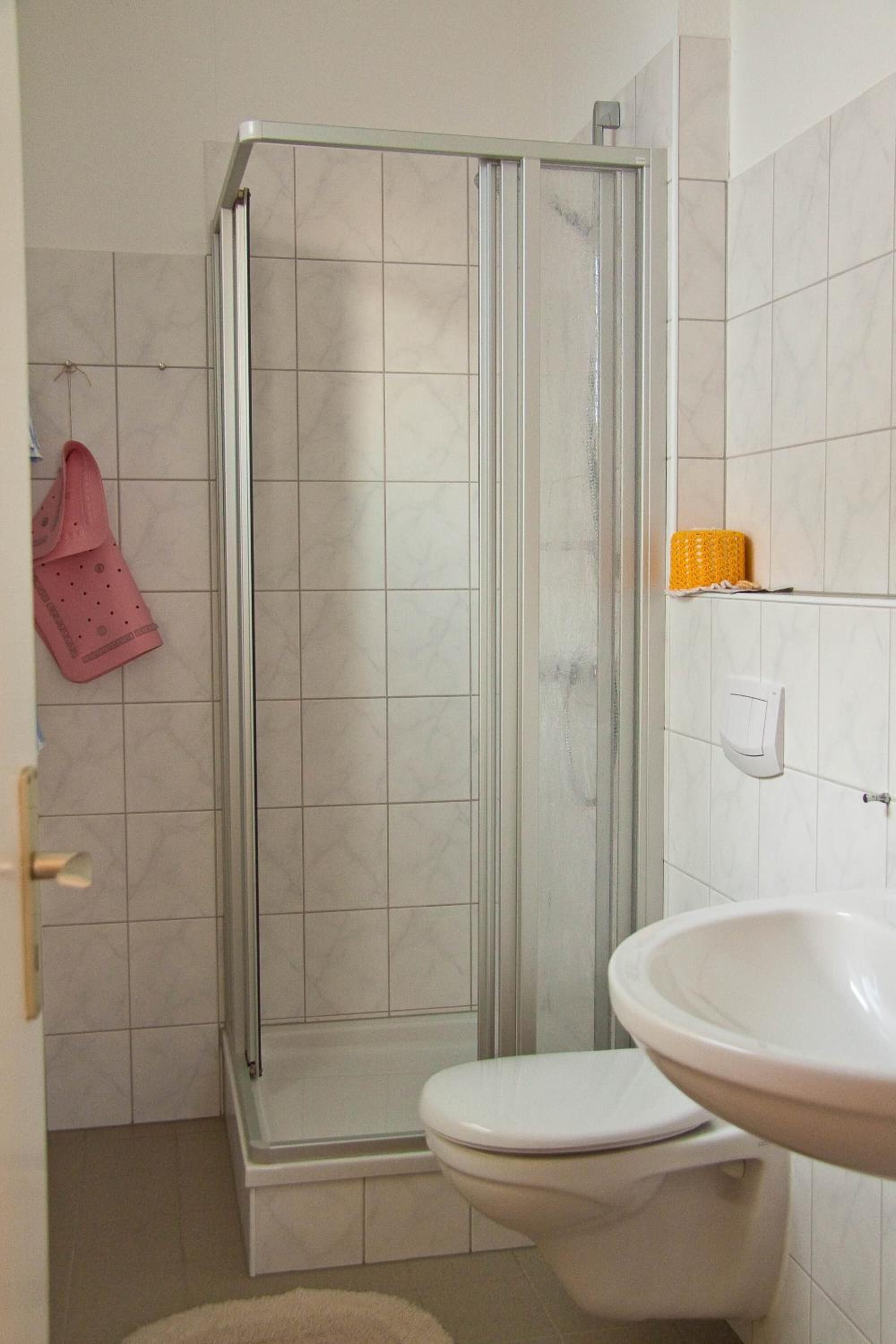 Une salle de bain avec une douche à parois de verre, des toilettes blanches et un lavabo.