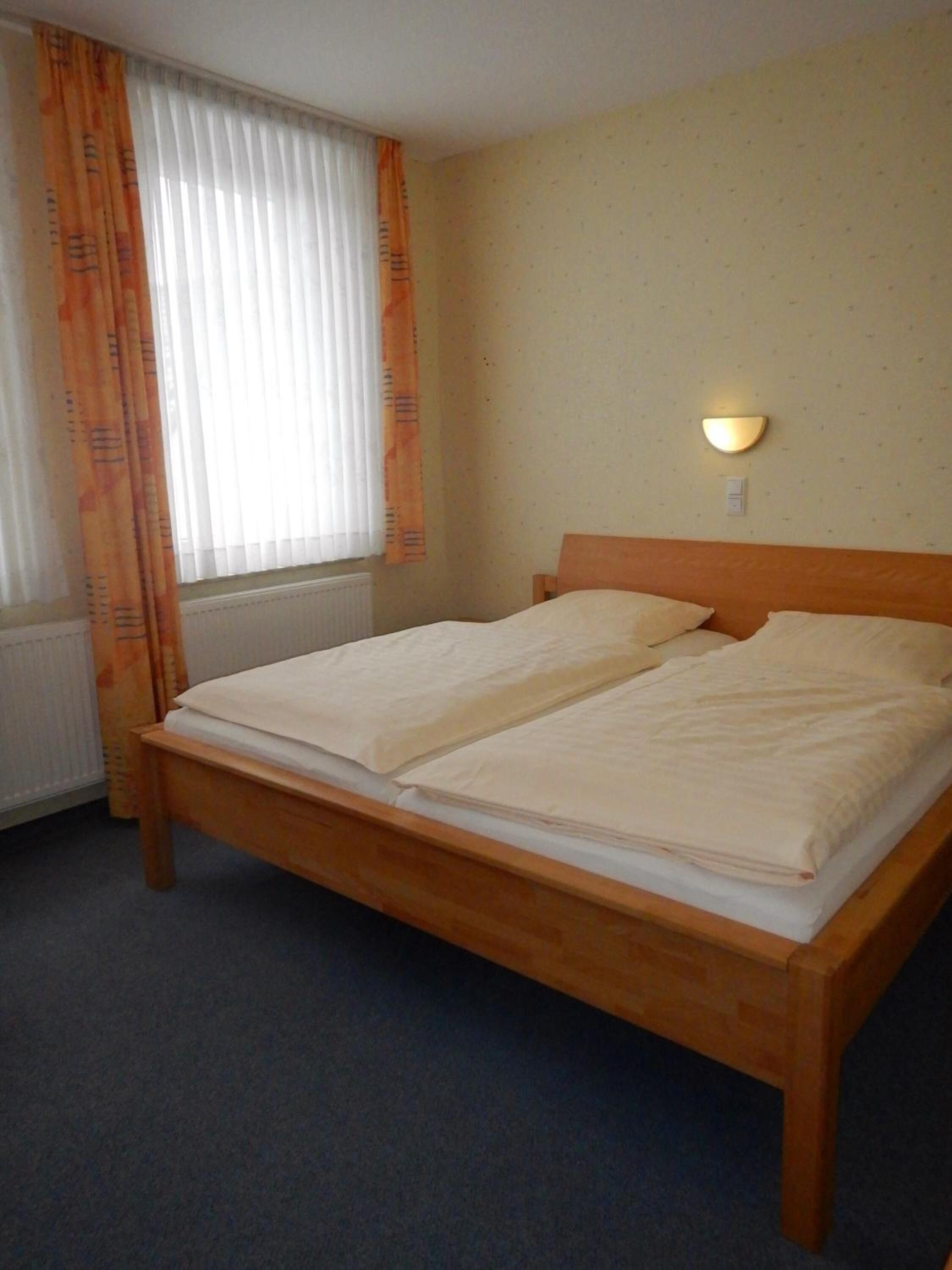 Ein Doppelbett in einem Hotelzimmer mit einem Holzkopfstück, einem Heizkörper und einer Wandleuchte.