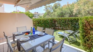 A patio with a table set for dining, surrounded by chairs and a glass table. - Family friendly apartment with pool, close to all amenities and the Pinewalk.  (Pollensa)