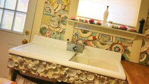 A bathroom with a sink surrounded by a wall of decorative plates and a mirror above it.