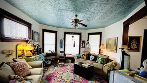 A cozy living room with a patterned carpet, a ceiling fan, and a variety of furniture including a sofa and a chair.
