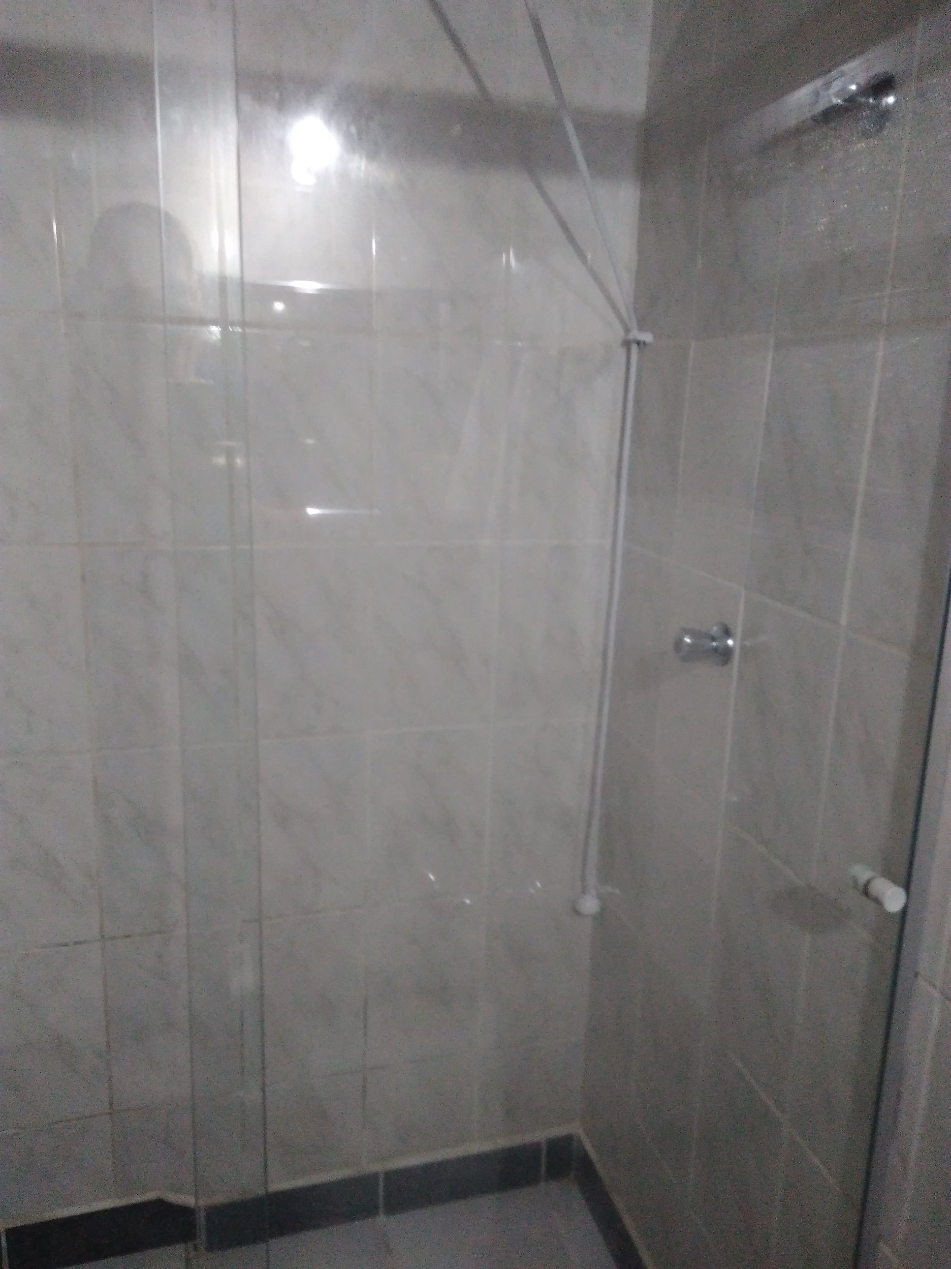 Una ducha con cerramiento de vidrio, paredes y piso de azulejos.