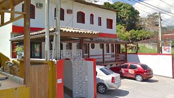 Un edificio de dos pisos con fachada roja y blanca, un porche cubierto y una entrada protegida por una reja.