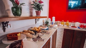Ein reichhaltiges Buffet mit verschiedenen Speisen und einem an der Wand montierten Fernseher.
