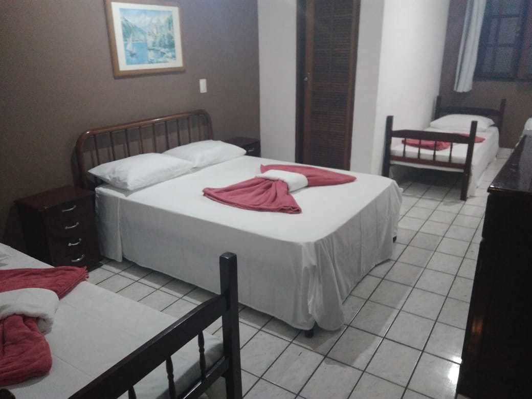 A hotel room with two beds, a wooden headboard, a small cabinet, and a framed picture on the wall.