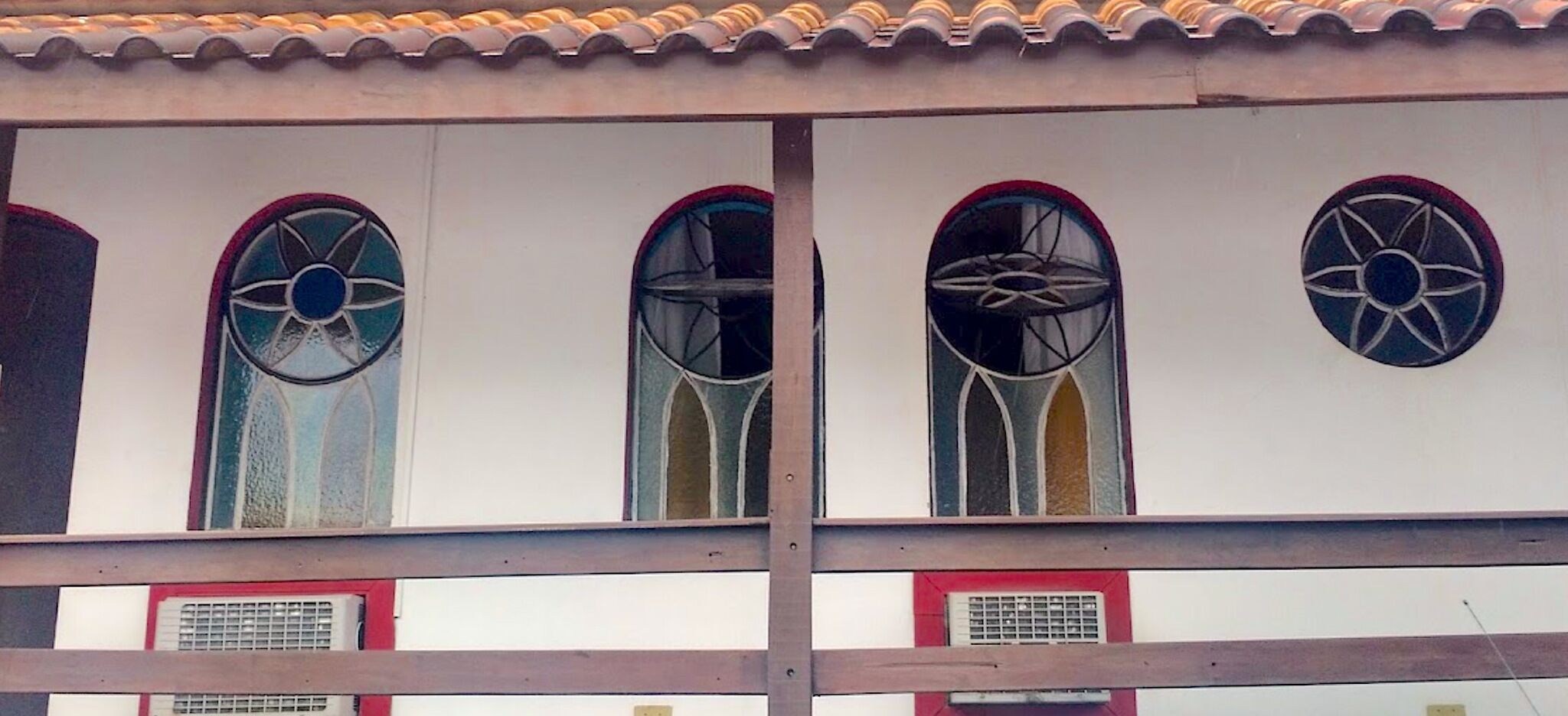 A building with four arched windows with decorative glass designs.