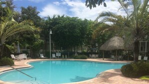 A swimming pool with a brick pathway, surrounded by palm trees and lounge chairs. - Key West - Stock Island  (Key West)