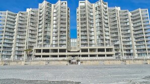A modern high-rise building with multiple balconies and a central courtyard. - One Ocean Place 1101! 
Book at 2024 Rates w/ VRBO all in pricing nightly rate! (Murrells Inlet)