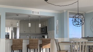 A kitchen with white cabinets, a microwave, and a hanging light fixture. - One Ocean Place 1101! 
Book at 2024 Rates w/ VRBO all in pricing nightly rate! (Murrells Inlet)