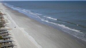A beach with a long stretch of sand and a few structures along the shore. - One Ocean Place 1101! 
Book at 2024 Rates w/ VRBO all in pricing nightly rate! (Murrells Inlet)