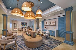 A spacious lobby with a curved sofa, multiple chairs, a dining area, and a kitchen counter.