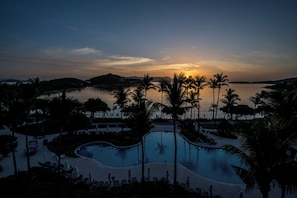 A resort pool with palm trees, a sunset, and a body of water. - 2 Bedroom - Ritz Carlton Club Residence (St Thomas)
