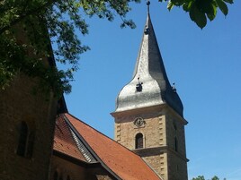 Eine Kirche mit einem hohen Kirchturm und einem Glockenturm.