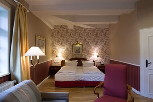 Una habitación de hotel con una cama, una silla, una lámpara y un cuadro en la pared.