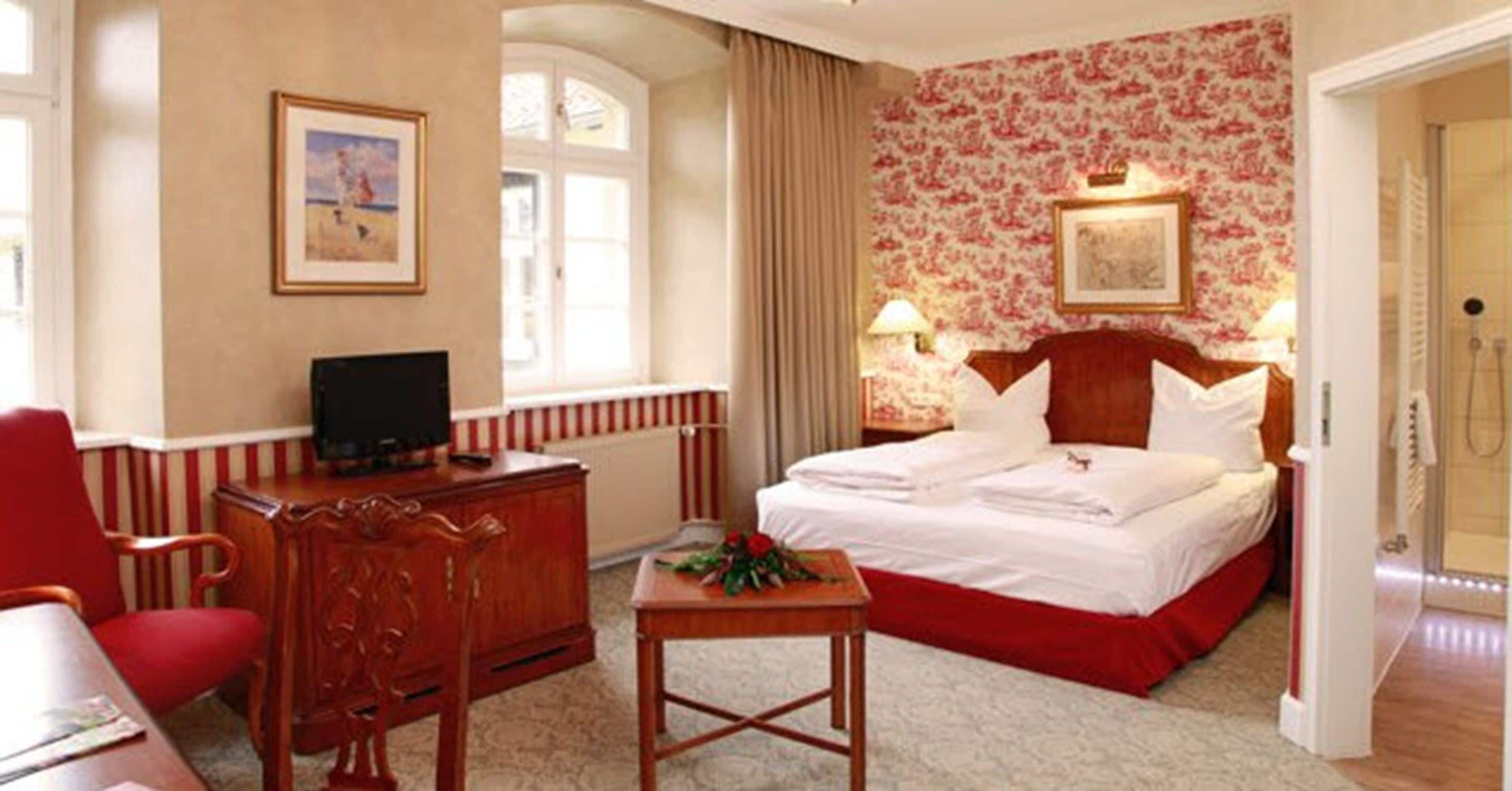 Habitación de hotel con una cama grande, un escritorio con silla, televisor y ventana con cortinas.