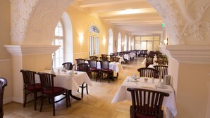 Un comedor con columnas decorativas, mesas y sillas de madera.