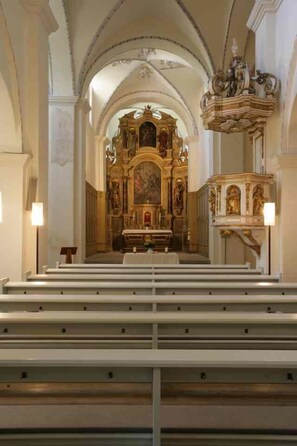 An interior of a church with a central altar, pews, and ornate decorations.