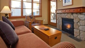 Una sala de estar acogedora con chimenea, sofás estampados y una mesa de centro de madera.