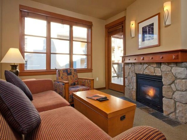 Una sala de estar acogedora con chimenea, sofás estampados y una mesa de centro de madera.