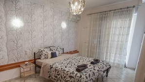 Une chambre à coucher avec un lit, une table de chevet, une couvre-lit à motifs et une fenêtre avec des rideaux.