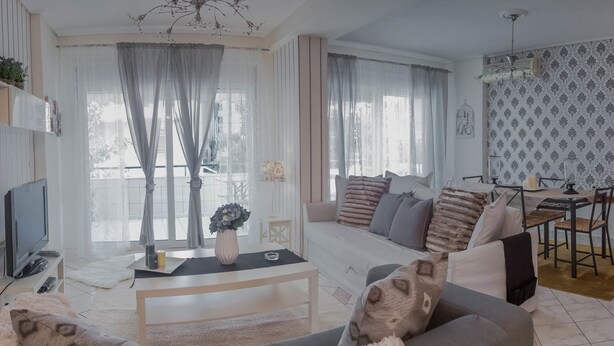 Un salon comprenant un canapé, une table basse et un téléviseur. Il y a également un coin repas avec une table et des chaises.