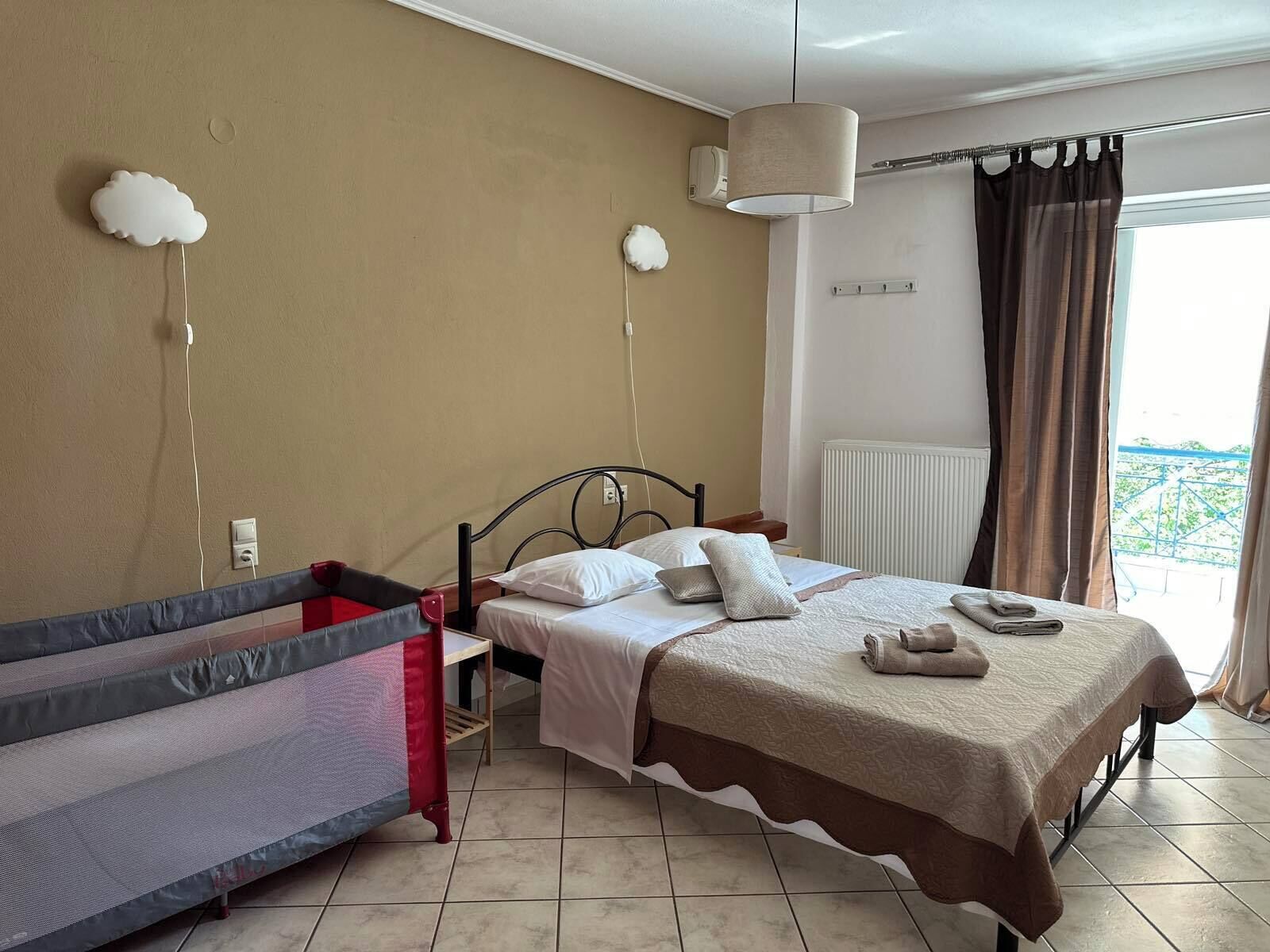 A bedroom with a bed, a small table, a chair, and a window with curtains.