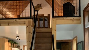 Een houten trap leidt naar een vide met uitzicht op de keuken en leefruimte.