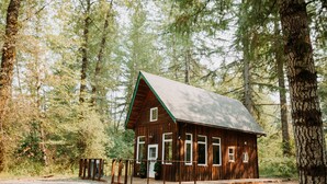 Een chalet met houten gevel, grote ramen en een veranda.