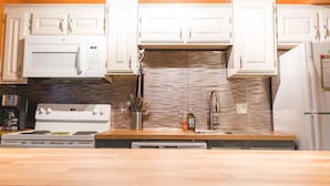 Una cocina moderna con armarios blancos, una campana extractora de acero inoxidable, un microondas, una estufa y un horno empotrado.