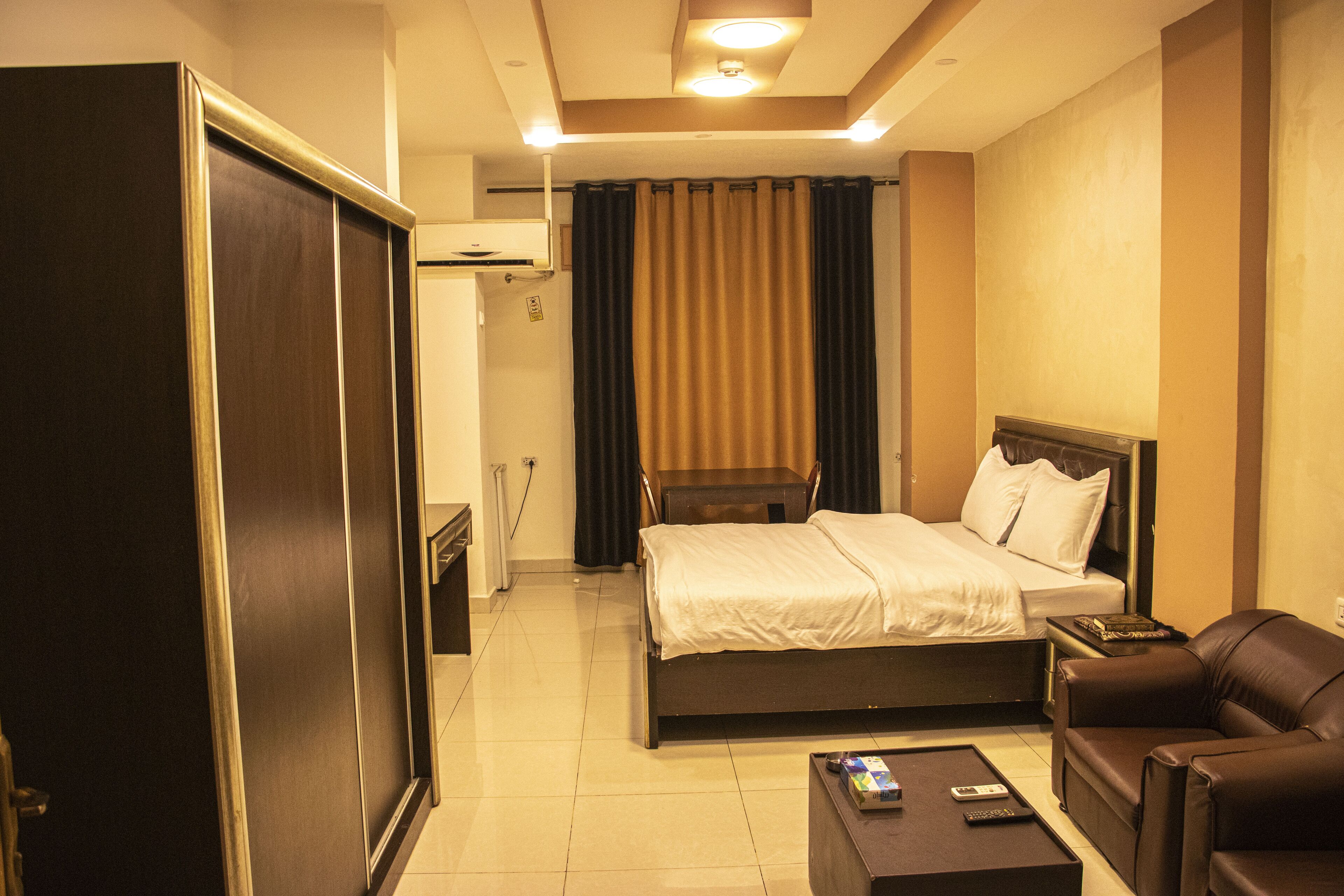 Una habitación de hotel con una cama, un sofá, una mesita de café y un armario.