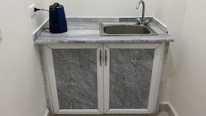 A small kitchen with a marble countertop, a sink, and a kettle. - Sara Crown Hotel (Irbid)