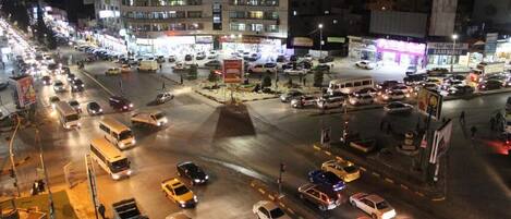 A busy urban intersection with multiple lanes of traffic and illuminated storefronts.