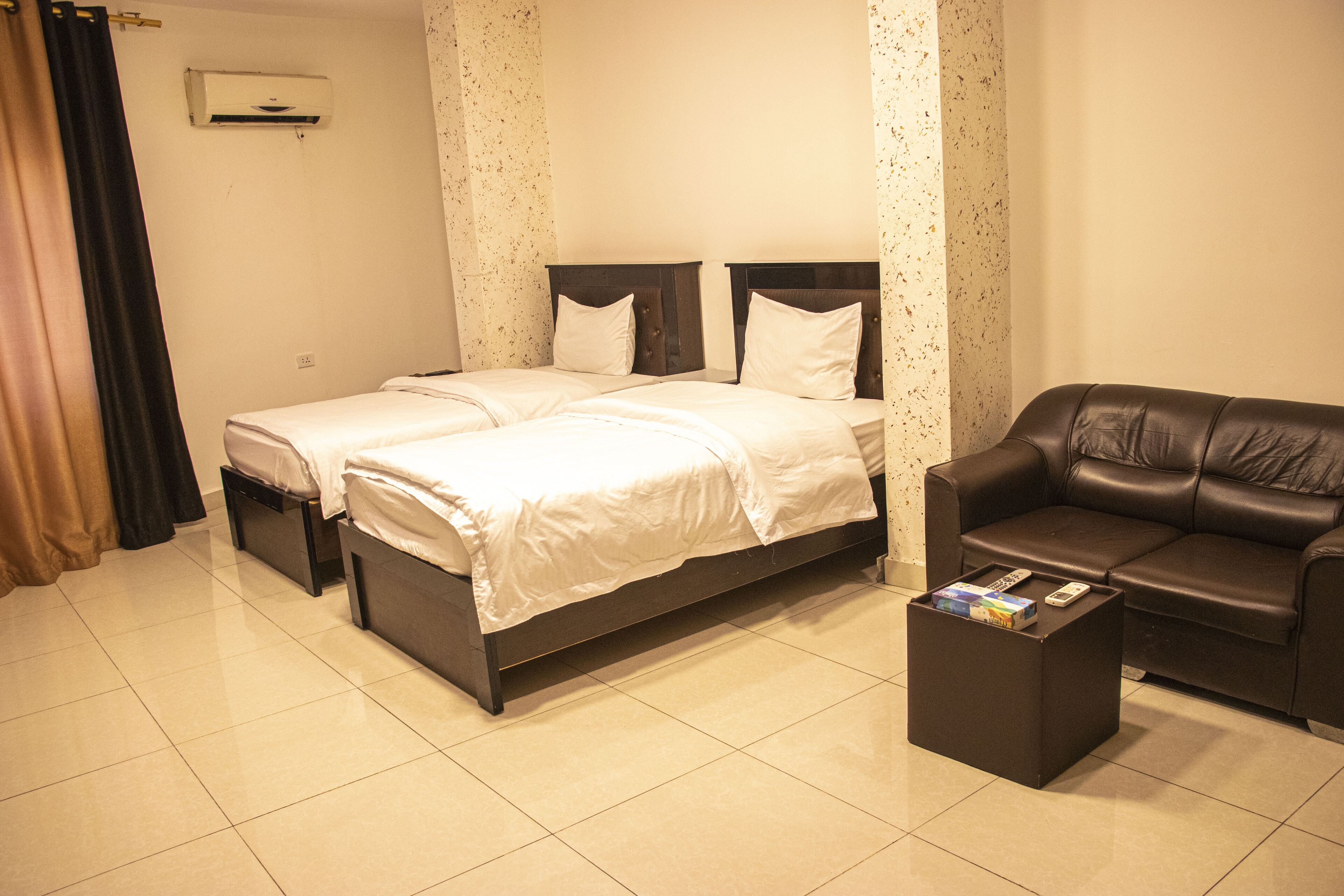 Habitación de hotel con cama doble, sofá de cuero y una mesita con un control remoto.