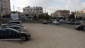 A parking lot with several cars and a fence. - Sara Crown Hotel (Irbid)