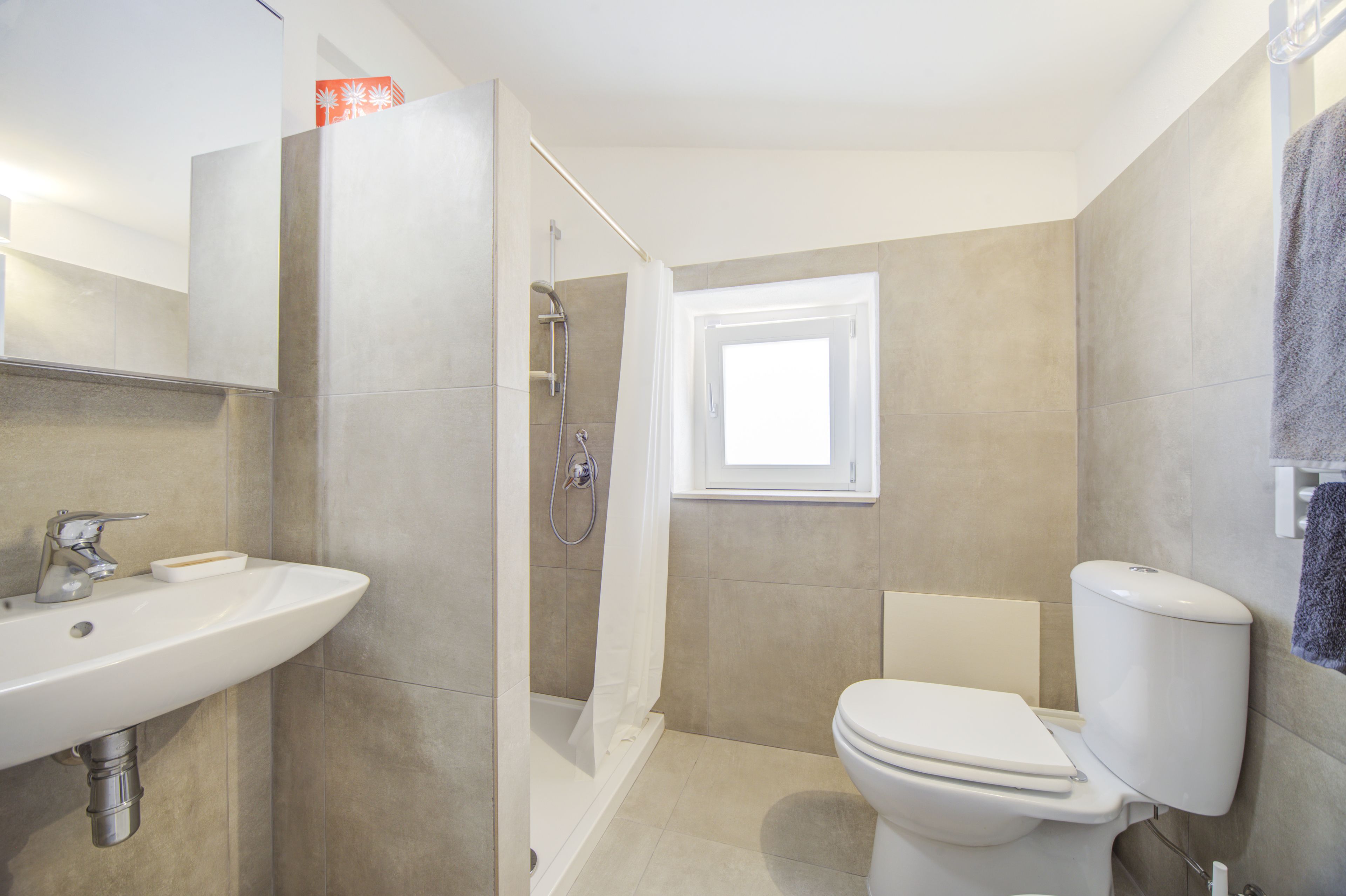 Une salle de bain avec un lavabo, des toilettes, une douche et une fenêtre.