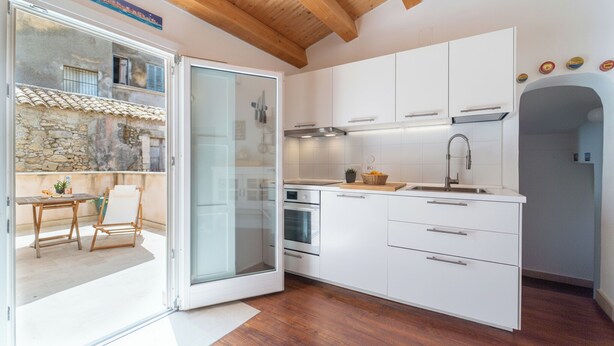 Eine moderne Küche mit weißen Schränken, einer Holztischplatte und einem eingebauten Backofen.