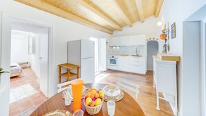 Eine moderne Küche mit weißen Schränken, Holzboden und einem Essbereich mit Tisch für zwei Personen.