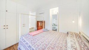 Ein Schlafzimmer mit Bett, Schrank und einer Tür zu einem weiteren Raum.