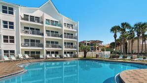 Un hotel con piscina, numerosi balconi e palme.