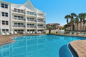 Ein Hotel mit Pool, mehreren Balkonen und Palmen.