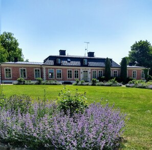 A two-story brick building with a symmetrical facade, large windows, and a central entrance.