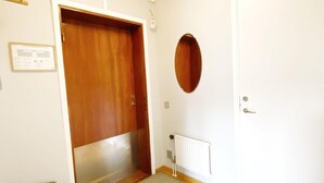 Ein Zimmer mit Holztür, weißem Heizkörper, kleinem Tisch und einer Holzbank.